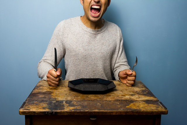 A man in grey jumper is shouting and slamming his knife and fork into the table at an empty plate’ 